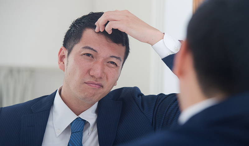 鏡を見て、薄毛を気にする男性