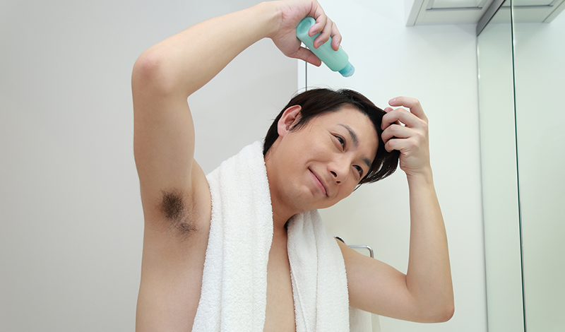 嬉しそうに育毛剤を使用する男性