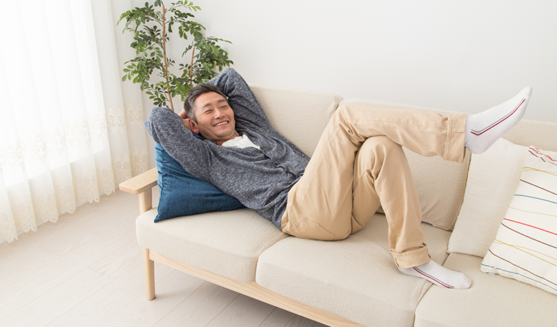 ソファーに寝そべり、リラックスする男性