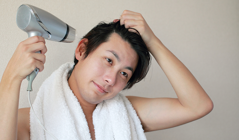 ドライヤーで髪を乾かす男性