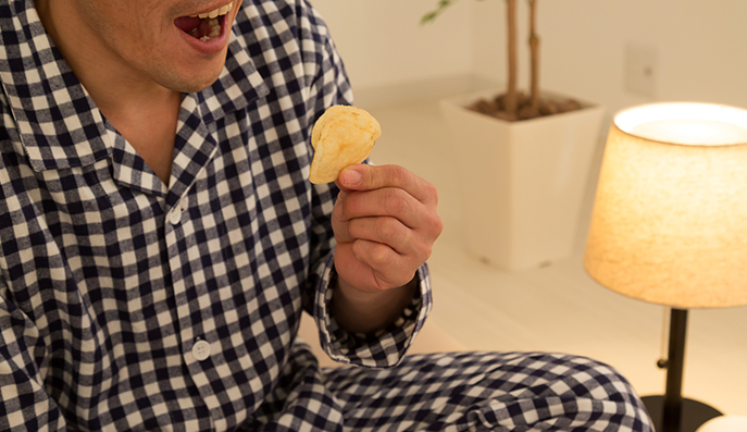深夜にポテトチップスを食べる男性