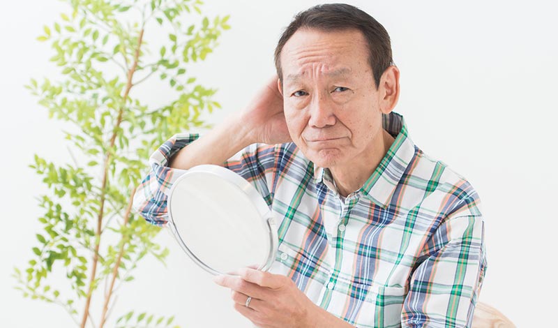 鏡を見て薄毛を気にする男性