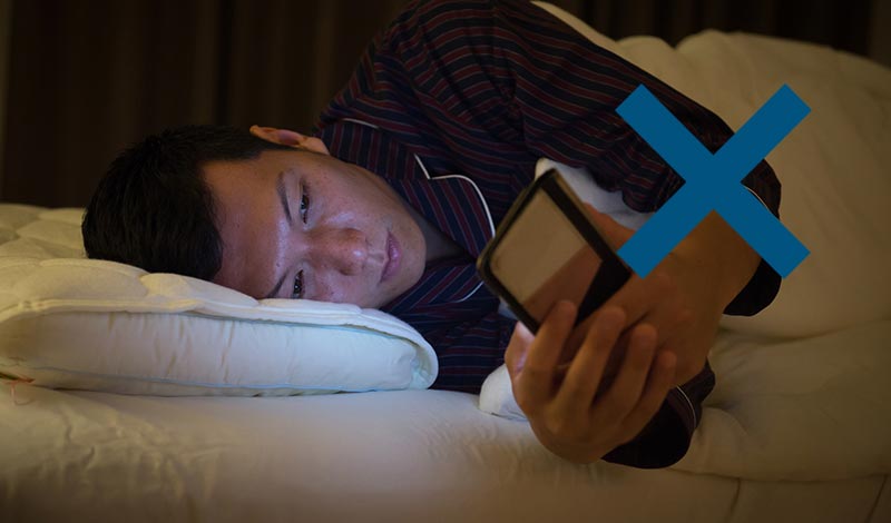 布団にはスマートフォンを持ち込む男性