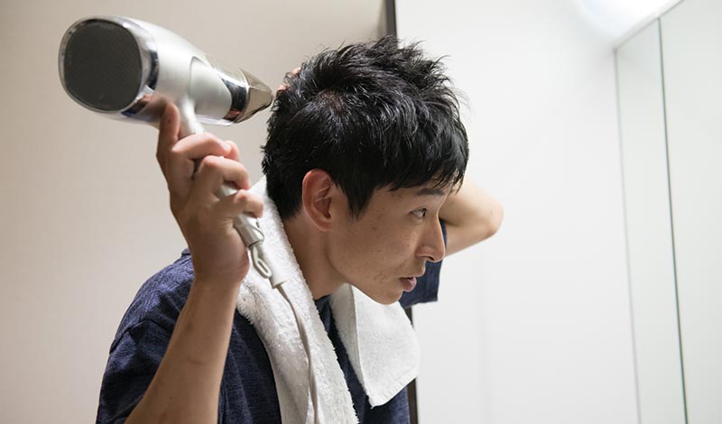 後頭部にドライヤーをあてる男性