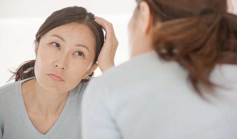 鏡をみて悩んでいる女性