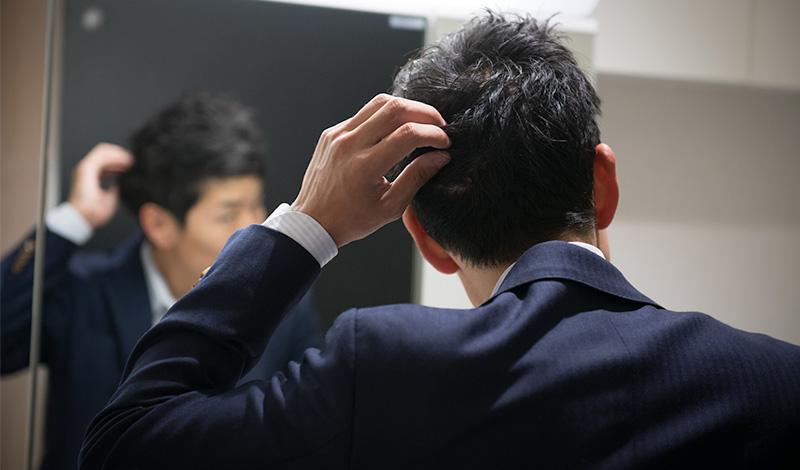 鏡の前で髪のチェックをする男性