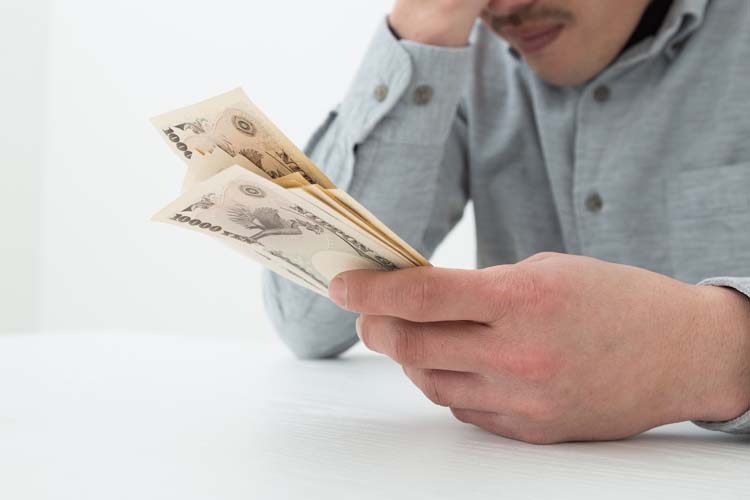 お金を手に持ち悩む男性