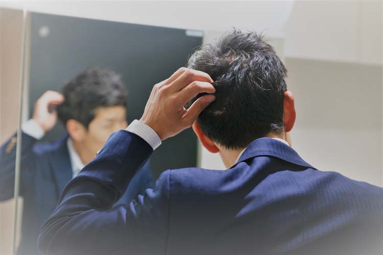 鏡で髪を気にする男性