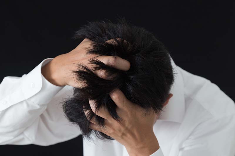頭を抱え悩む男性