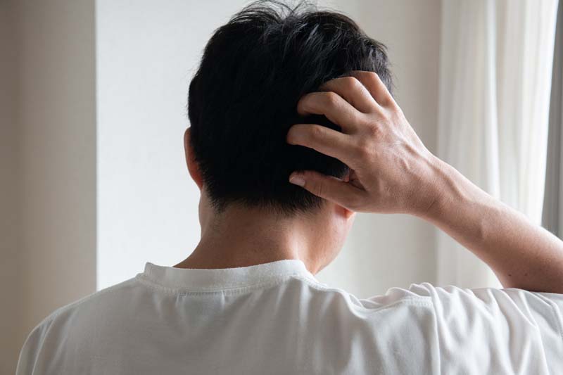 頭をかかえ悩む男性