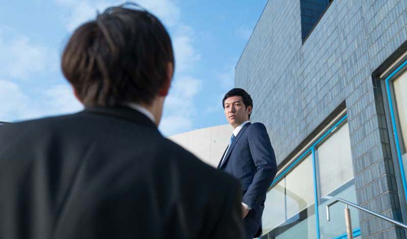 階段で先輩社員を見上げる
