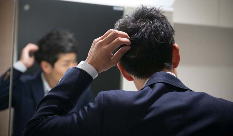 鏡をみて自分の髪を気にする