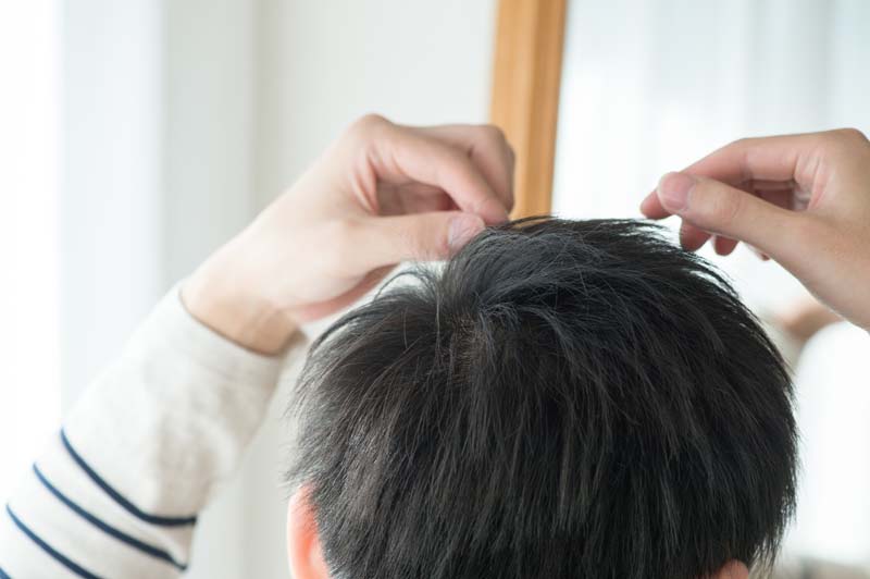 髪先をつまむ男性