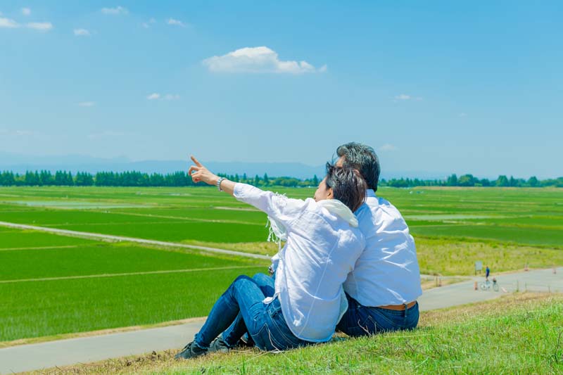 芝生の上で寄り添い談笑する男女