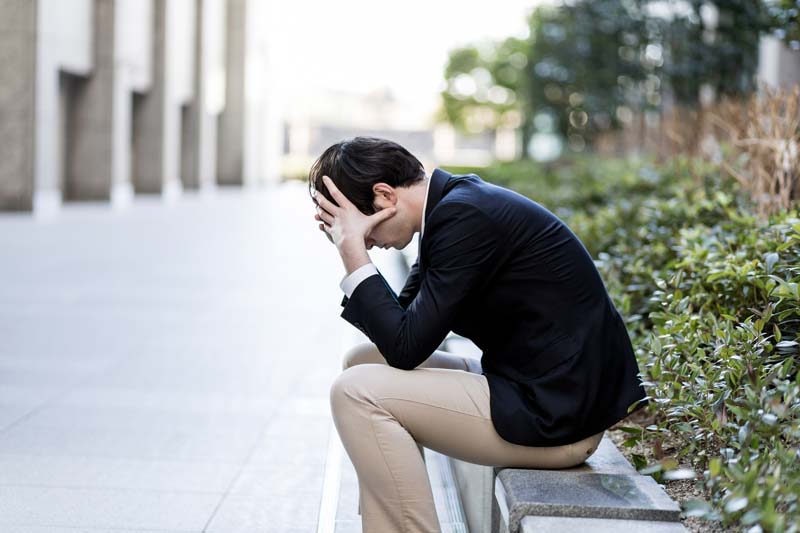 路肩で頭を抱える男性