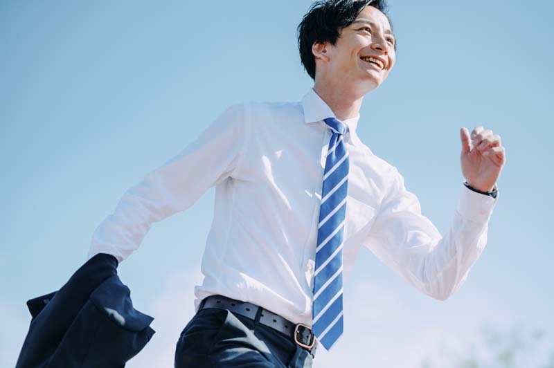 笑顔で走り出すビジネスマンの姿