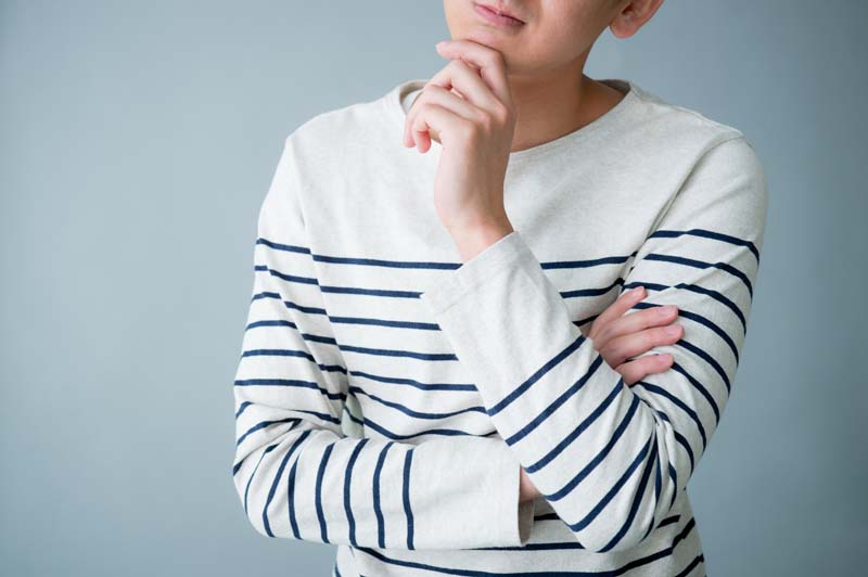 腕を組んで顎に手を添えた、疑問を抱えたようなポーズの男性