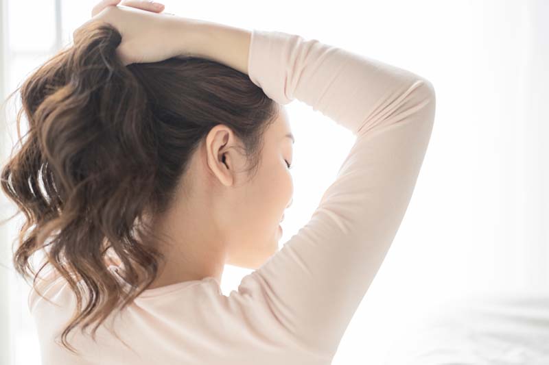 ポニーテールのヘアアレンジをしている最中の女性の姿