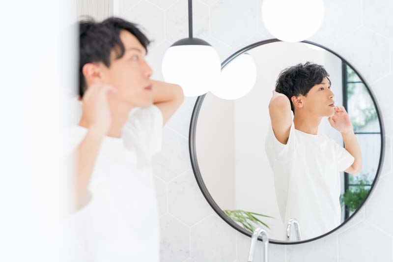 髪の毛を気にする男性が鏡に映る姿