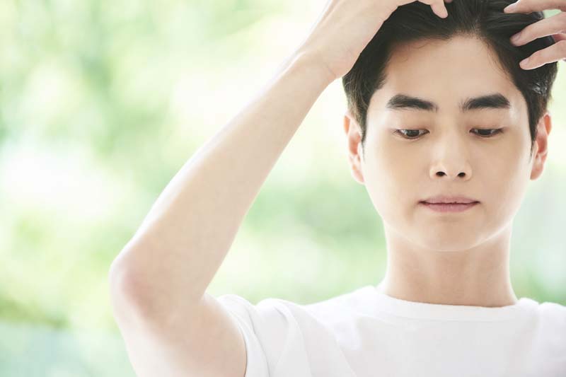髪の毛に触れている男性の写真