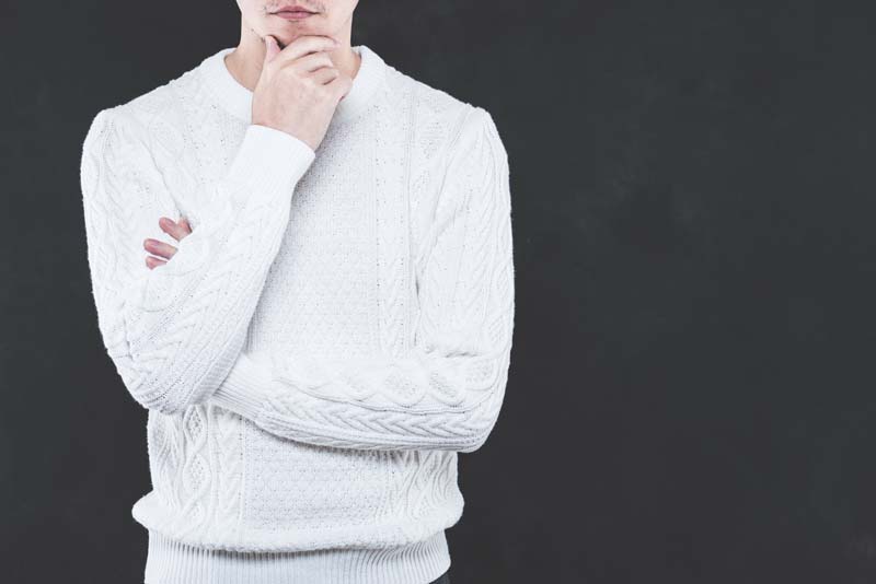 腕を組んで顎に手を当てた男性の姿