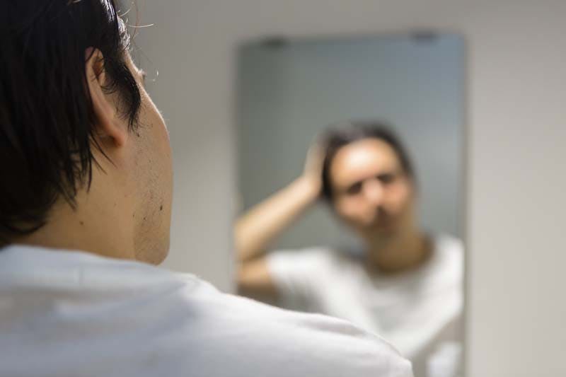 頭髪を気にする男性のイメージ画像