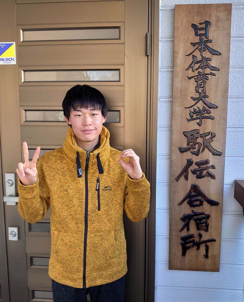 手で「20」の文字を作る藤本珠輝　日本体育大学駅伝合宿所の玄関前