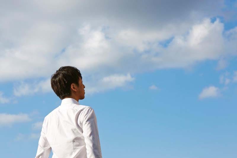編み込み式増髪の愛用者である男性が、青空を仰いでいる姿