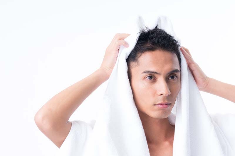 男性がタオルで頭髪を拭く様子