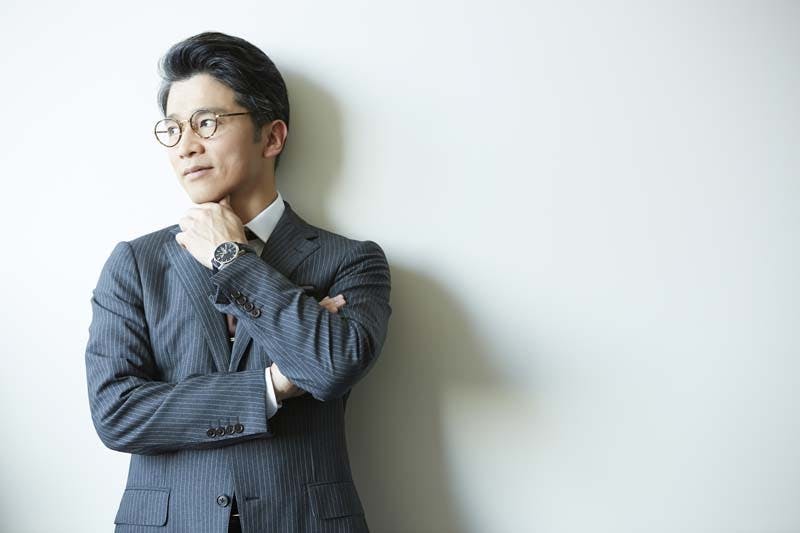 グレーのスーツを着た男性が左を向いて考え事をしている様子