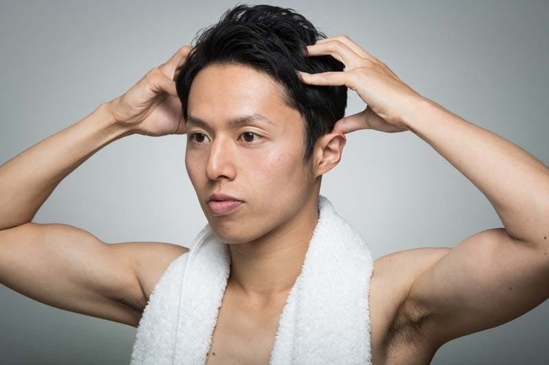 男性が頭皮マッサージのセルフケアをする様子