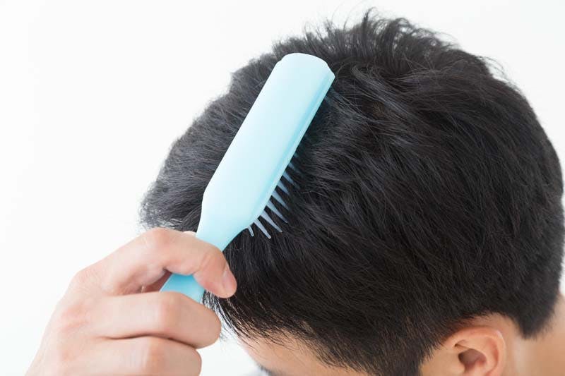 増毛後にブラシでヘアスタイルを整える男性画像