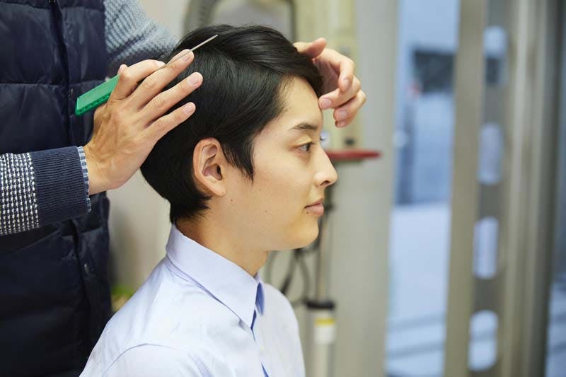 増毛後のメンテナンスをしている男性画像