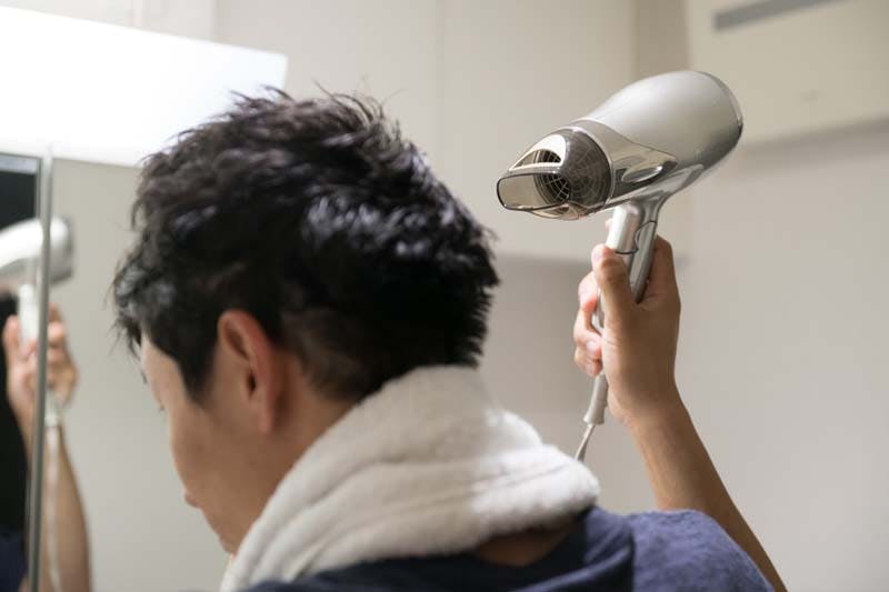 シャンプー後にドライヤーをかける男性画像