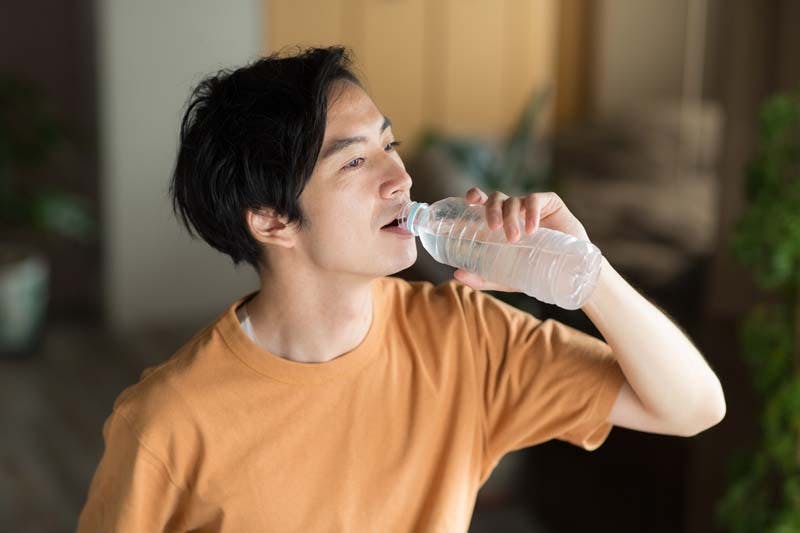 オレンジのTシャツを着た男性が水分補給をしている様子