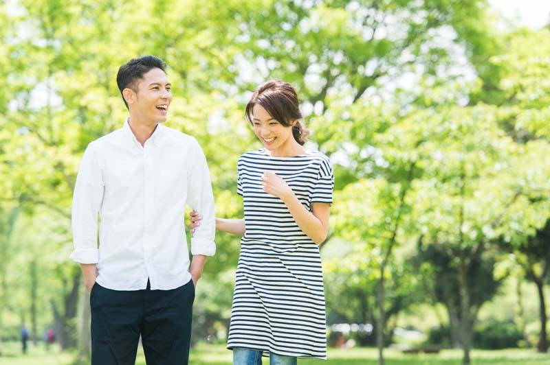 仲良く公園を散歩する男女カップルのイメージ画像