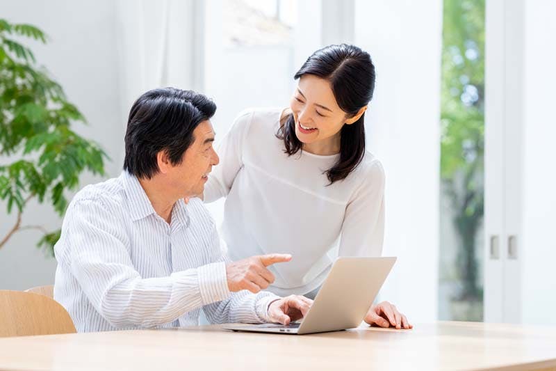 パソコン画面をチェックしながら会話している旦那さん・奥さまのイメージ画像