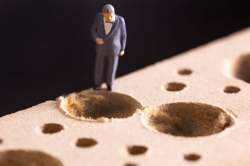 大きな穴を前にためらう男性のイメージ画像