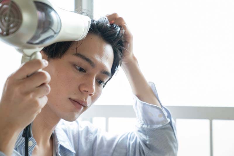 髪の毛をドライヤーで乾かす男性のイメージ画像