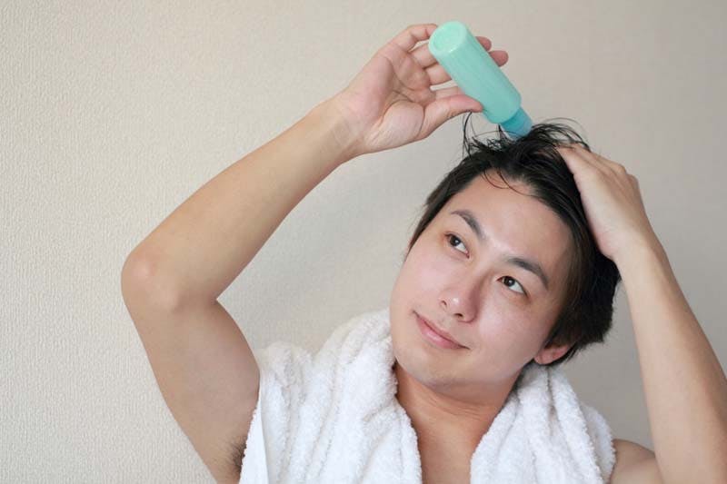 頭皮に育毛剤を塗布している男性のイメージ画像