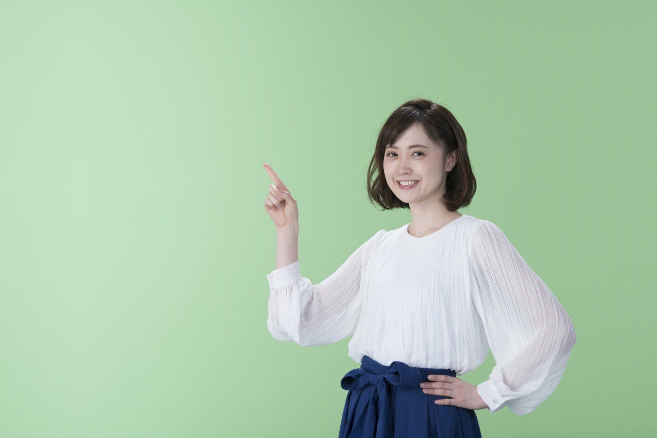 人差し指を立てる笑顔の女性の写真