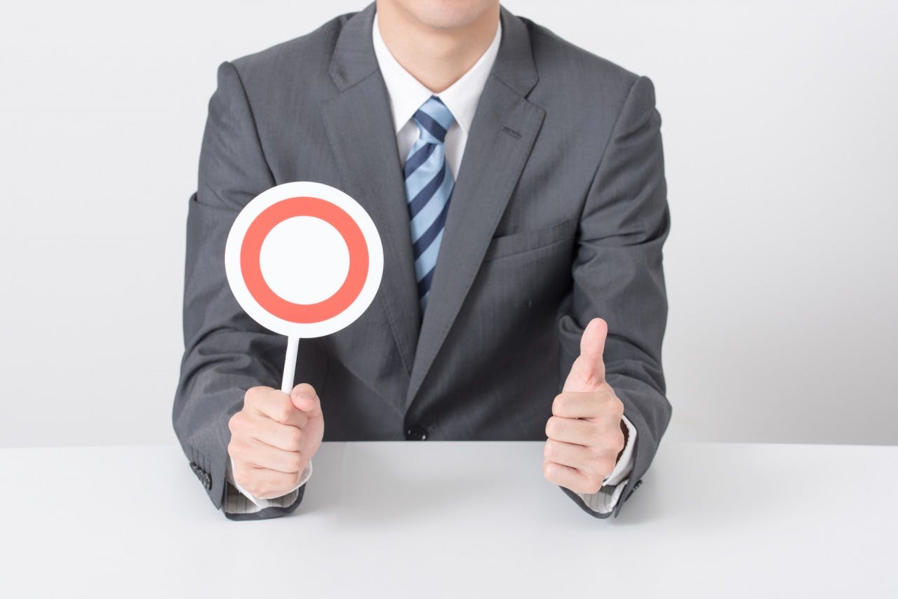 マルのプラカードを持って親指を立てる男性