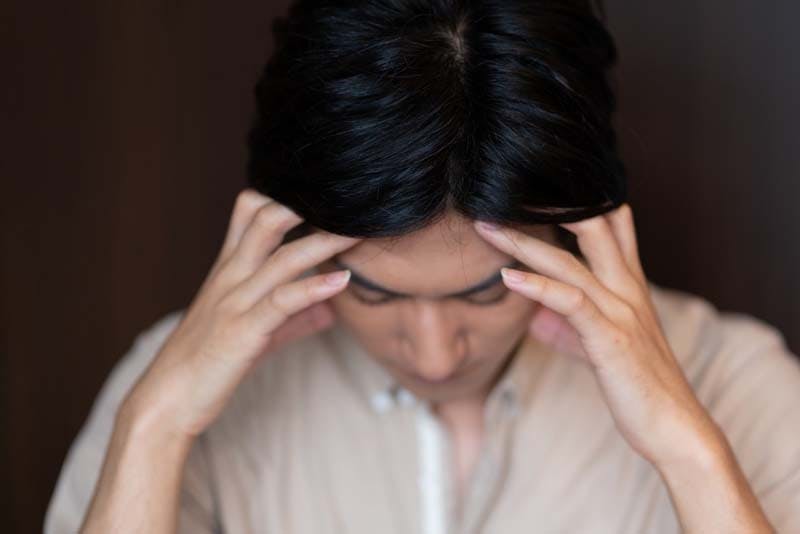 頭に手を当てて落ち込む男性のイメージ画像
