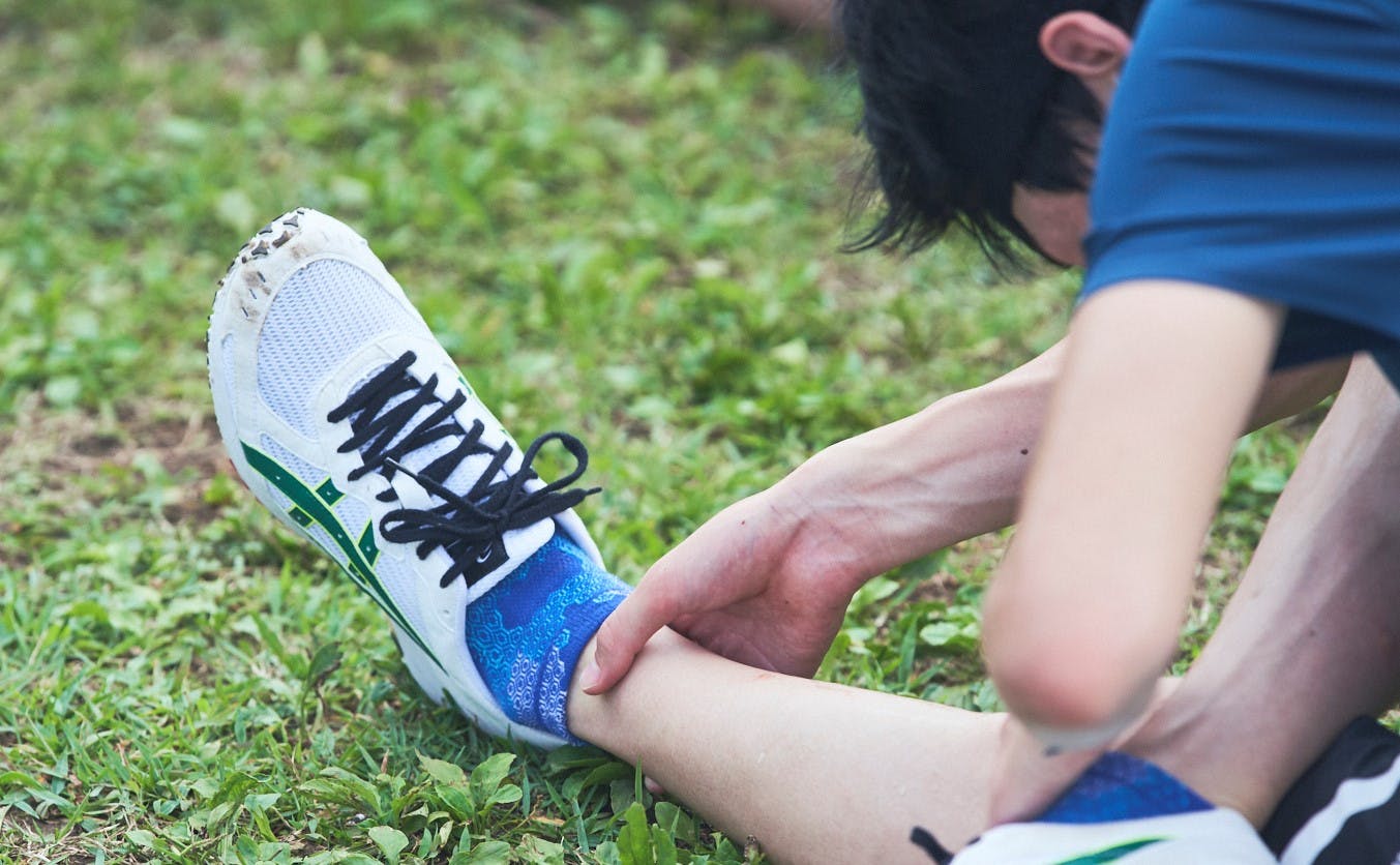 藤本珠輝選手が足首に手を添えながらストレッチする様子