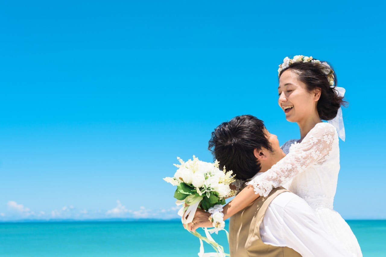 海辺で新婦を抱きかかえる新郎の写真