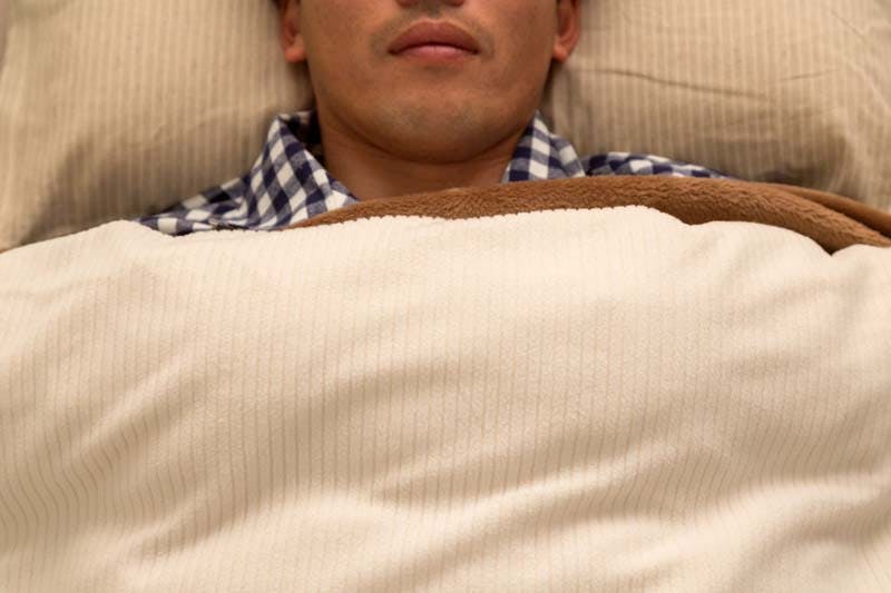 仰向けに寝る男性のイメージ画像