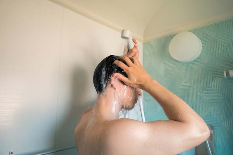 朝にシャンプーをする男性のイメージ画像