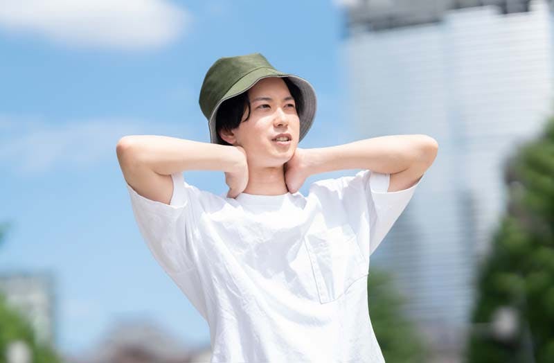 晴天下で帽子を被る男性のイメージ画像