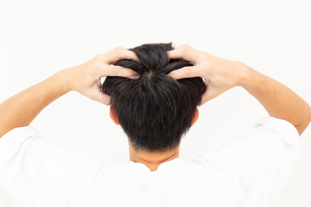 頭皮マッサージを行う男性の後頭部（つむじ）