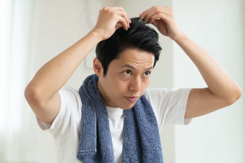 頭皮の乾燥をチェックする男性の画像